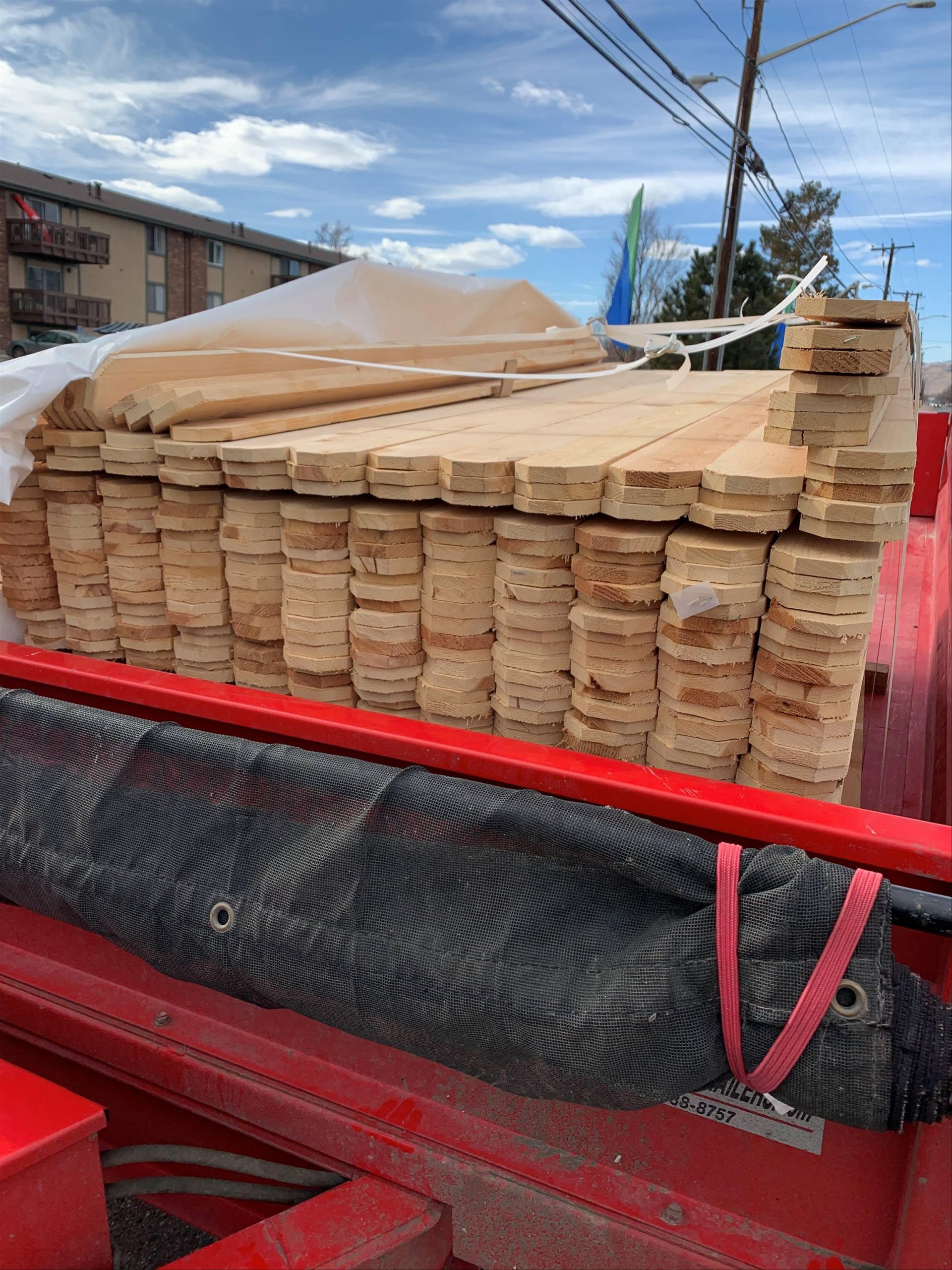 Stacked wood fence pickets loaded on a trailer for commercial fence repair project in Denver Colorado