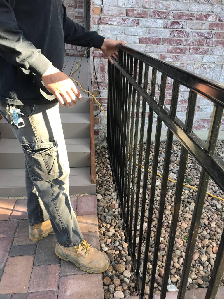 Technician repairing a damaged steel commercial fence at a Denver property to restore security
