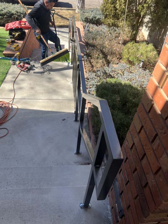 Denver Fence installer securing hardware on a custom metal handrail installation