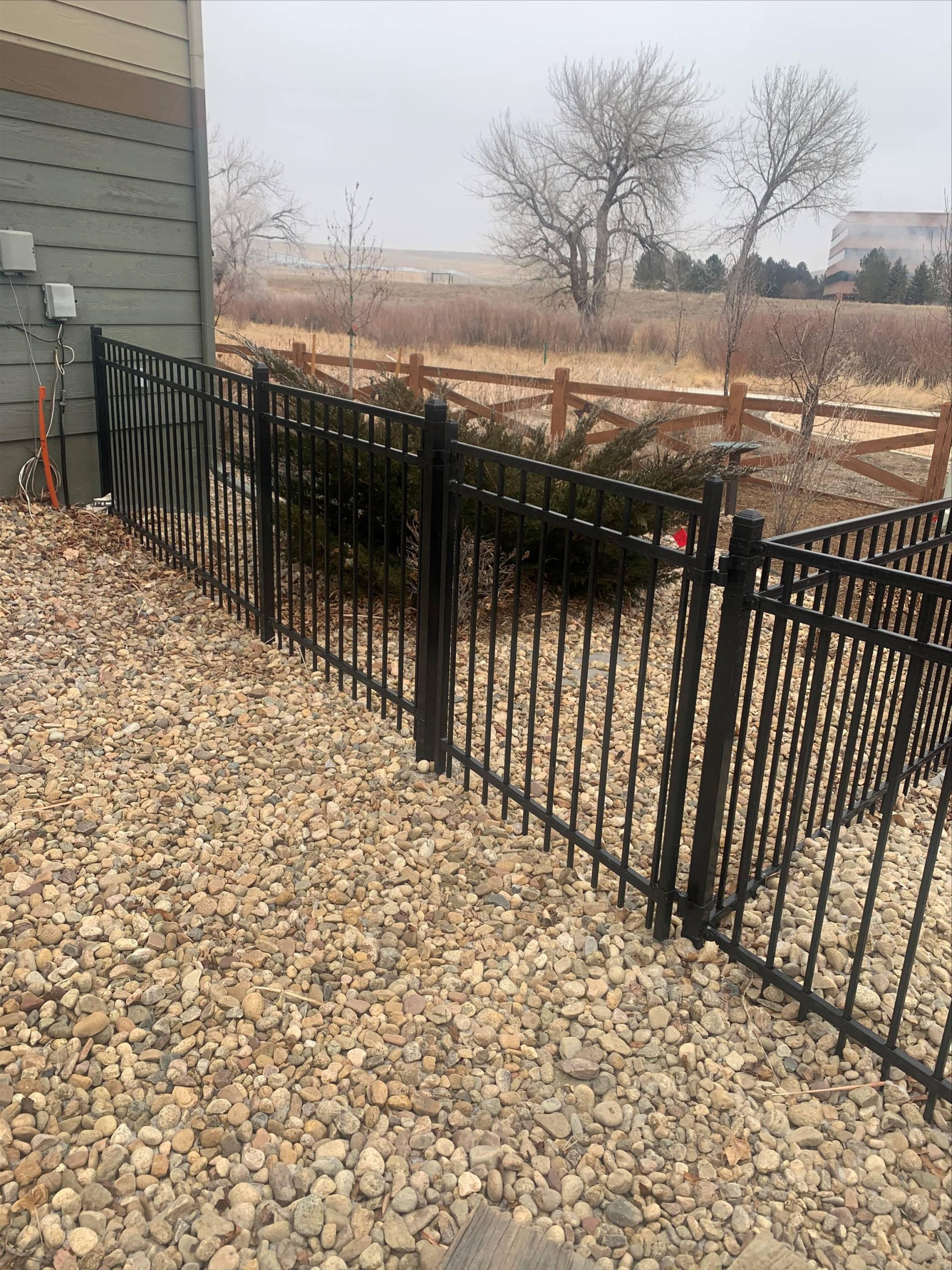 Ornamental metal gate and fence installed beside rock landscaping in the Denver metro area