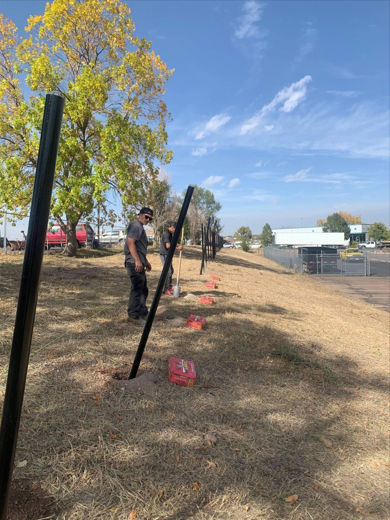 Heavy equipment installing steel fence posts during commercial project in Denver