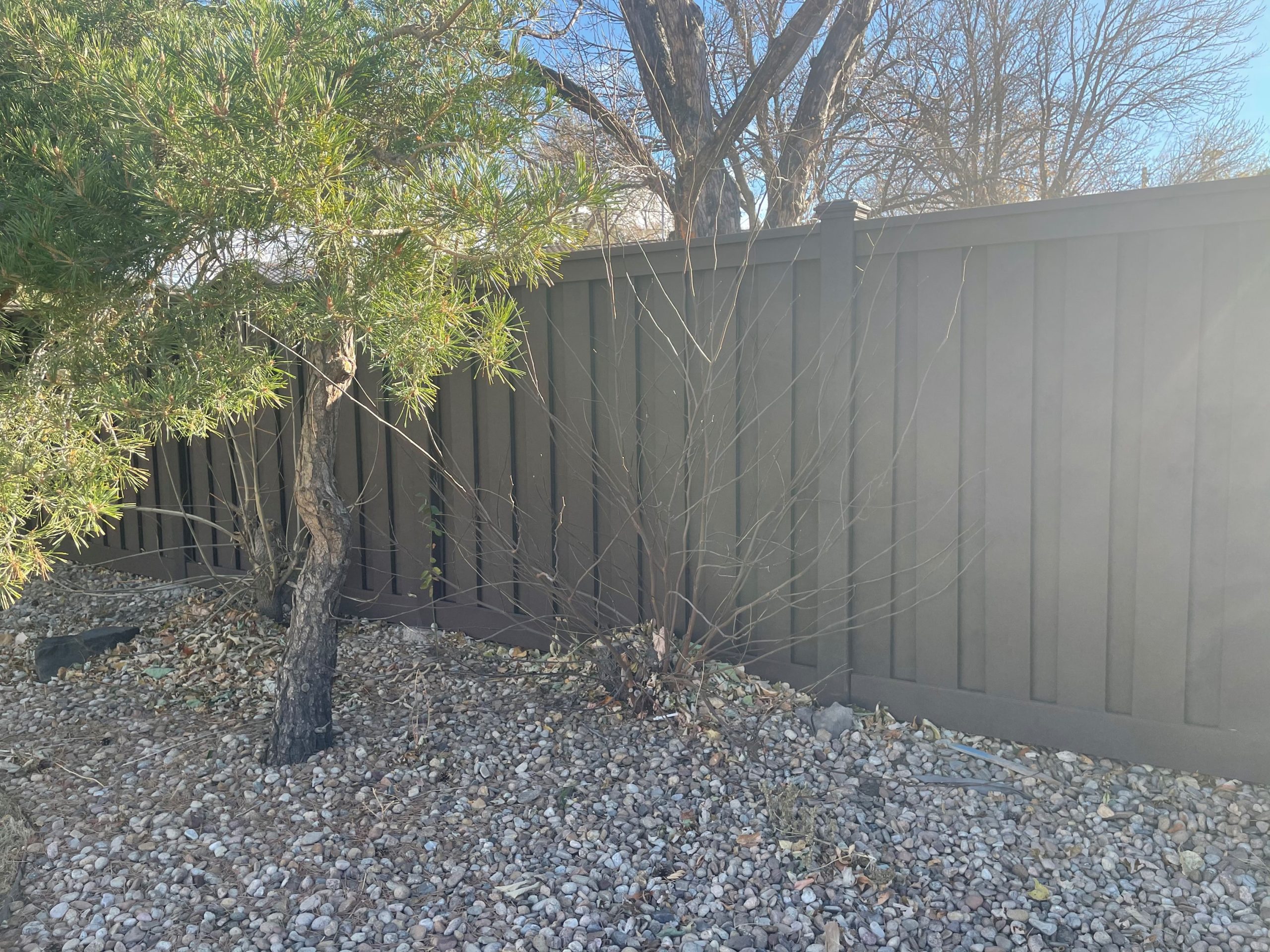 Dark brown Trex composite privacy fence installed along residential property line in Lakewood CO with clean landscaping